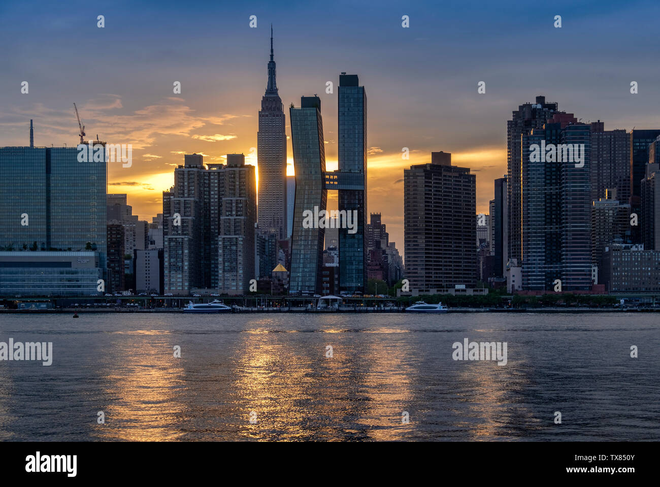 L'horizon de Manhattan et l'Empire State Building à travers l'East River au coucher du soleil, Manhattan, New York, USA Banque D'Images