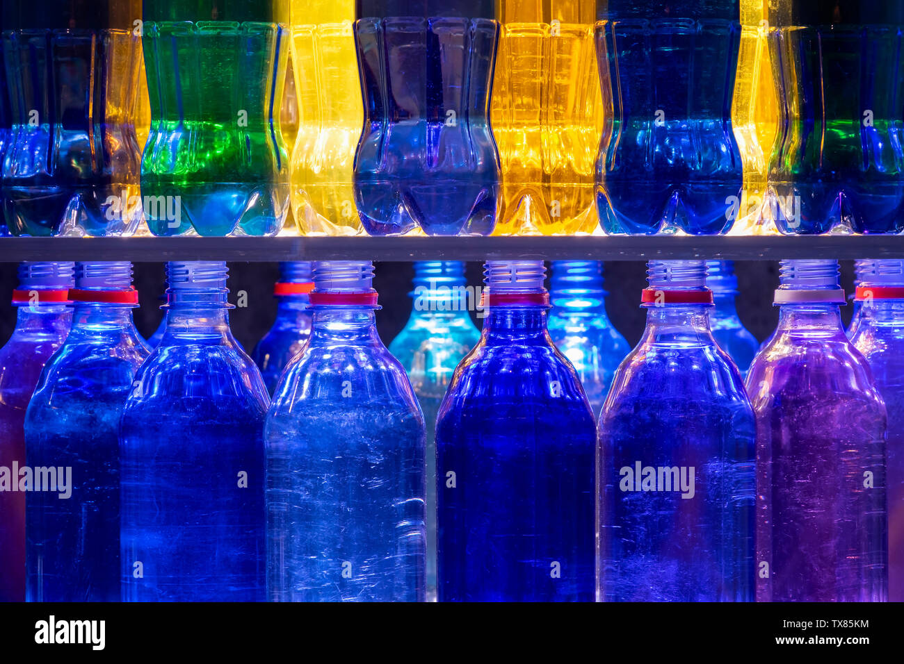 Les bouteilles en plastique colorés empilés sur des étagères Banque D'Images