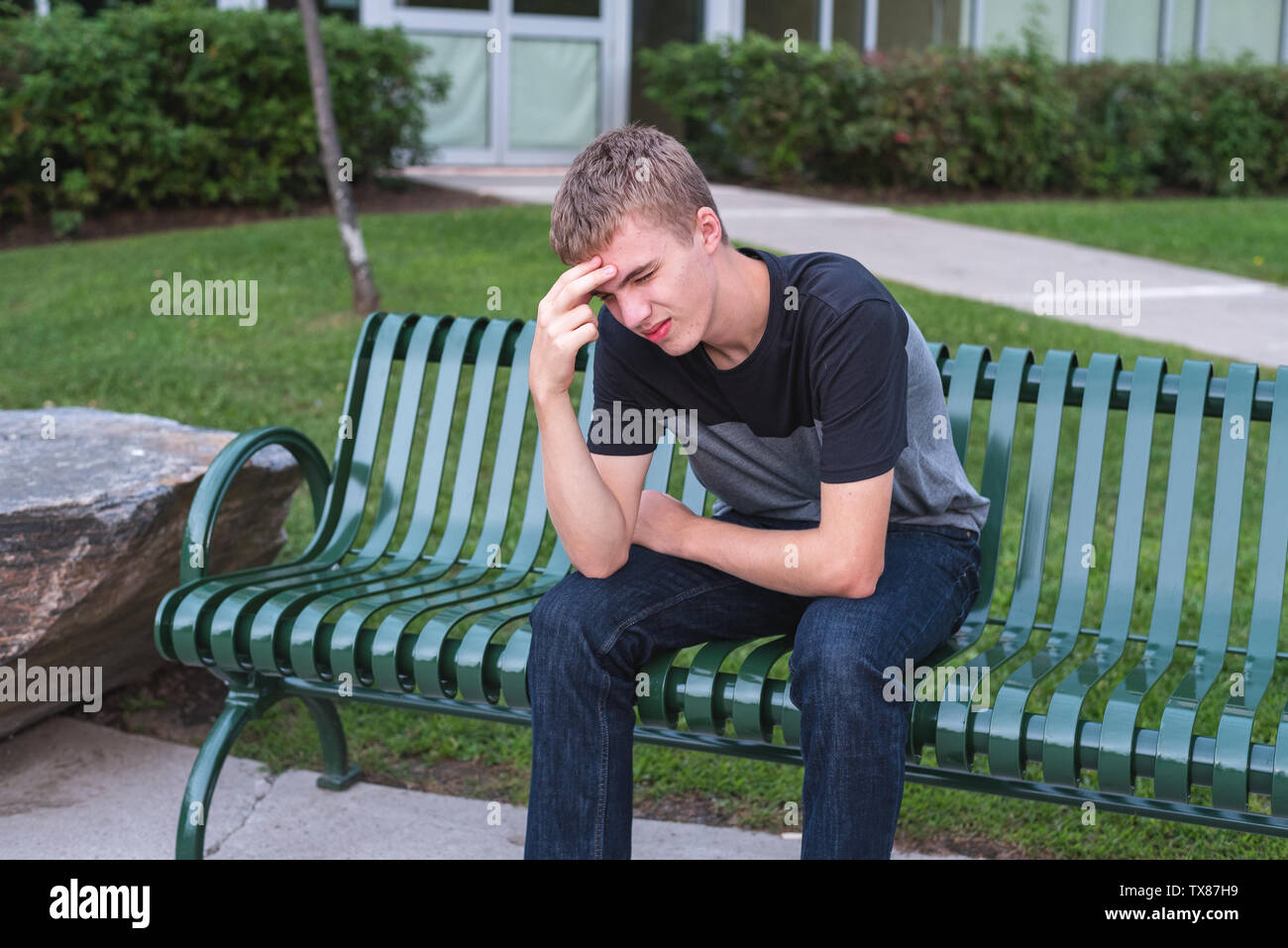 Adolescent perturbé assis sur un banc tout seul. Banque D'Images