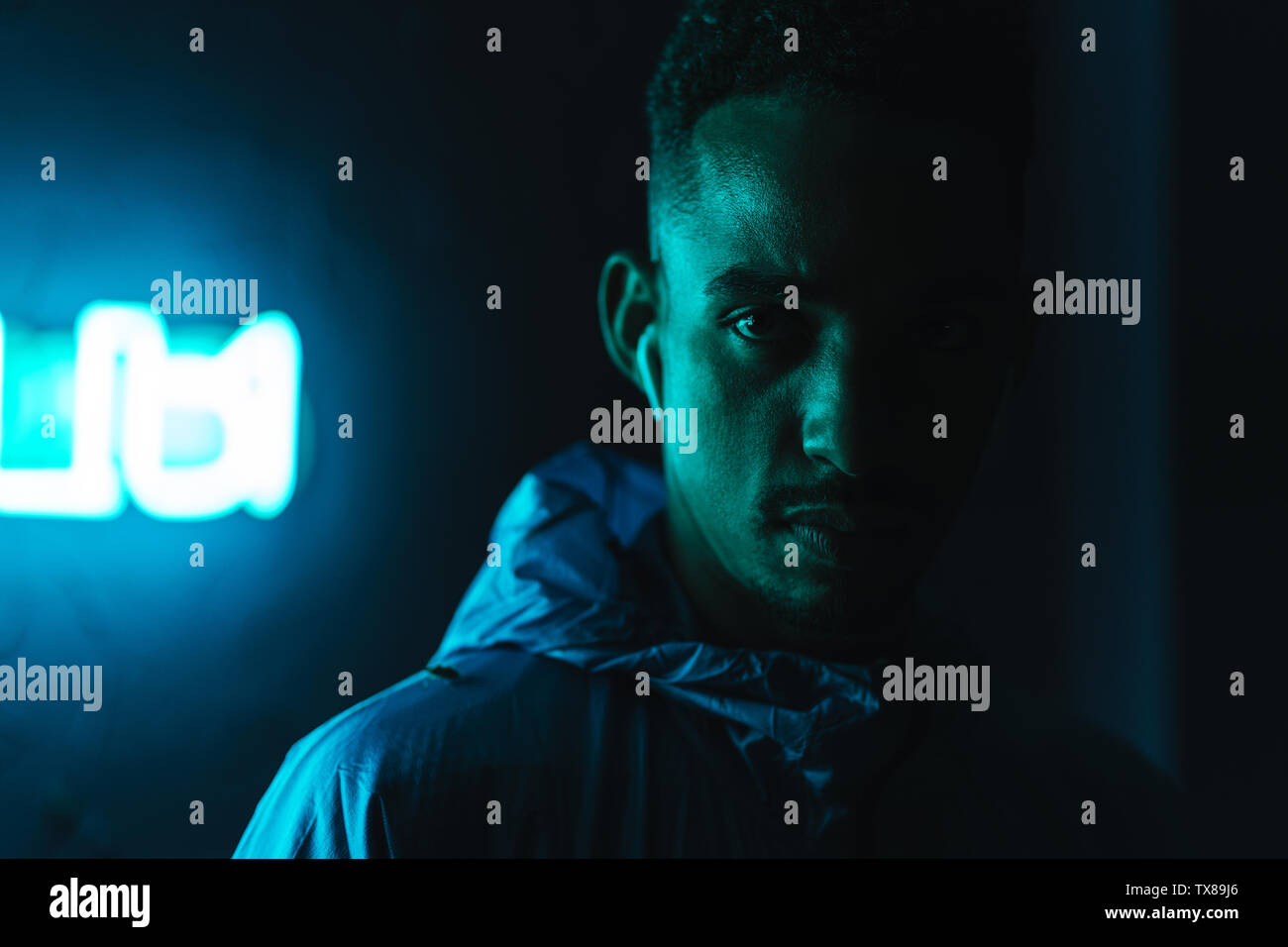 Close up d'un certain jeune homme africain portant un coupe-vent debout à l'extérieur près d'une enseigne au néon Banque D'Images