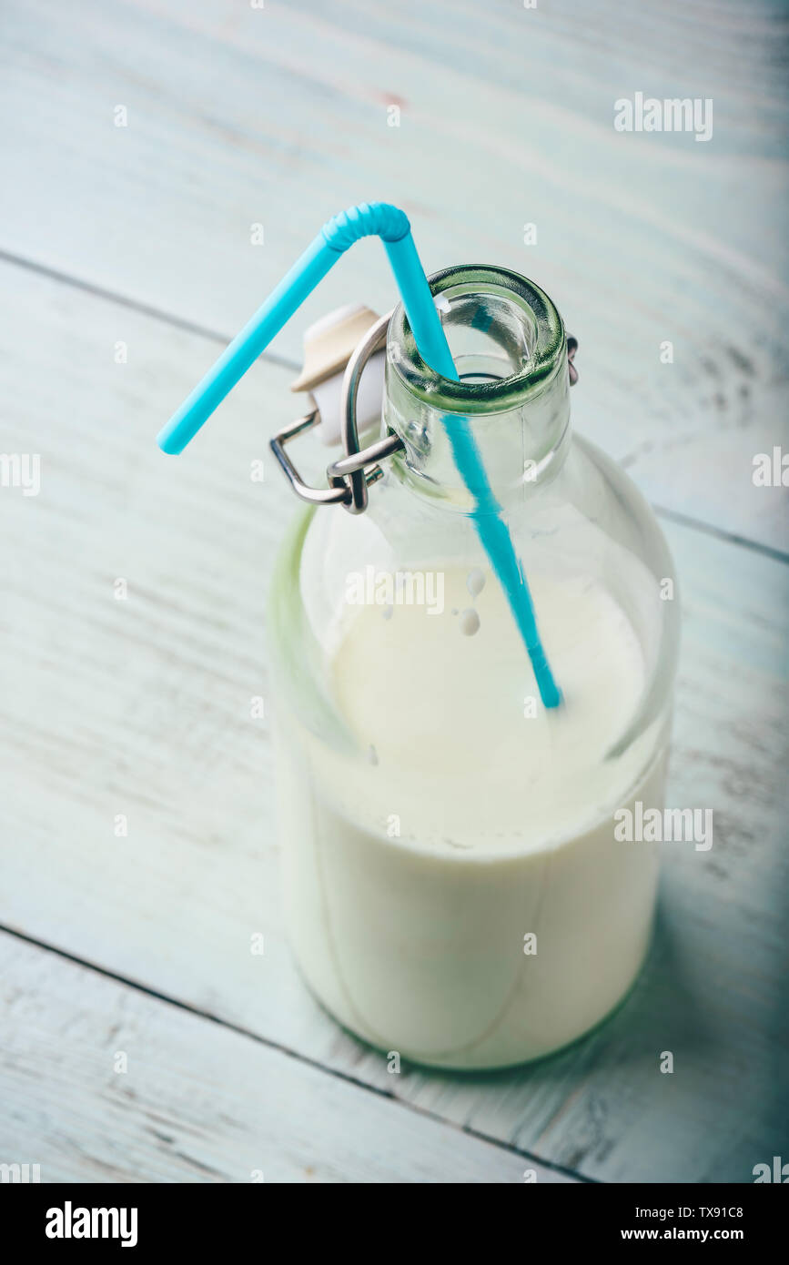 Le lait en bouteille de verre avec paille bleu Banque D'Images