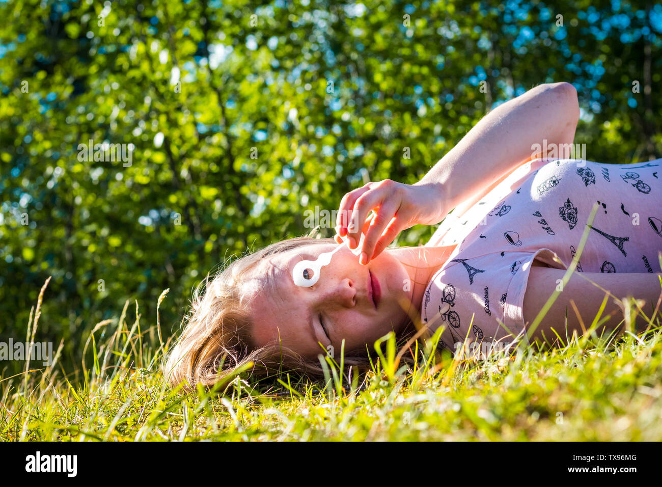 Belle et jeune fille souffle des bulles de savon. La jeune fille se trouve sur l'herbe verte dans le contexte de la forêt. Banque D'Images