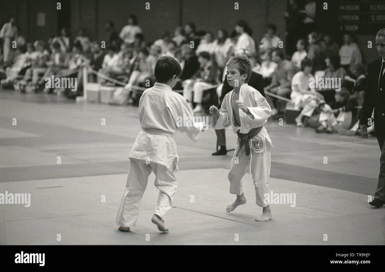 Années 1980, historiques, deux jeunes garçons Vêtements de coton blanc dans la compétition sur un mat à un événement judo, England, UK. L'art martial a été créé au Japon en 1882 comme un exercice mental et physique par son fondateur Jigoro Kano et est maintenant un sport olympique ayant été démontré lors de la 1932 de 2010. Pourtant, son fondateur Kano était ambivalent à ce sujet, car il croyait que le Judo a été beaucoup plus qu'un simple sport, d'être un moyen de réalisation culturelle personnelle, Banque D'Images