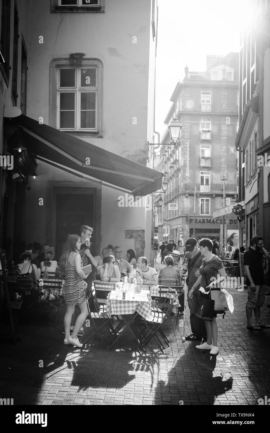 Strasbourg, France - 22 juillet 2017 : Grand groupe de personnes sur piscine restaurant café terrasse sur 6 Rue du vieux Seigle mangeant à l'Epicerie du soleil avec flare droit - noir et blanc Banque D'Images