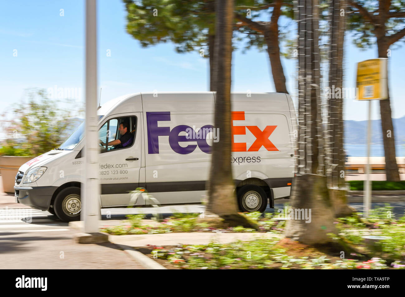CANNES, FRANCE - Avril 2019 : FedEx delivery van roulant le long de la route en bord de mer à Cannes, avec une vitesse d'obturation lente permet de blur motion. Banque D'Images