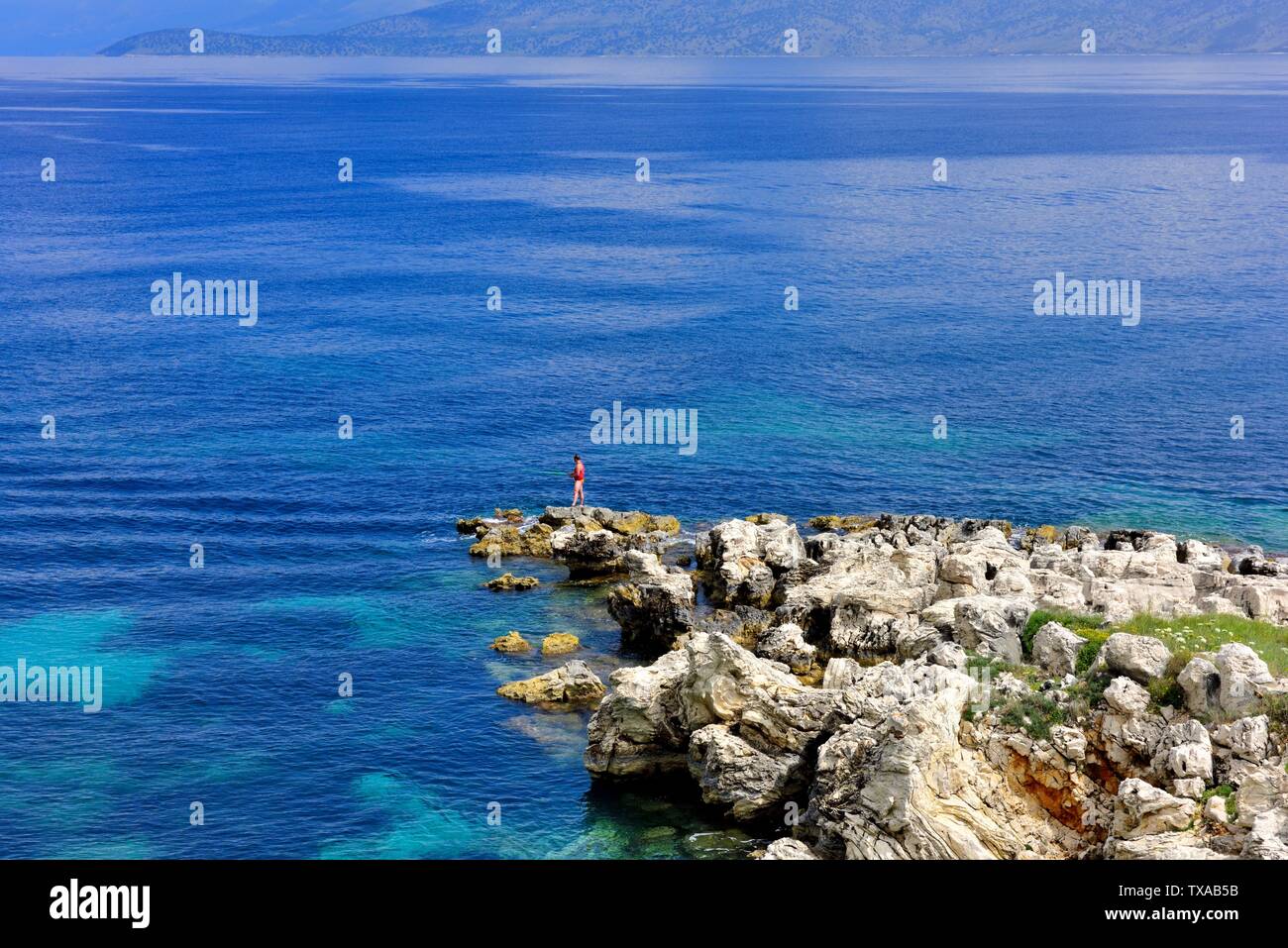 Un homme de pêche quelques roches à Kassiopi,Kassopaia,Îles Ioniennes, Corfou, Grèce Banque D'Images