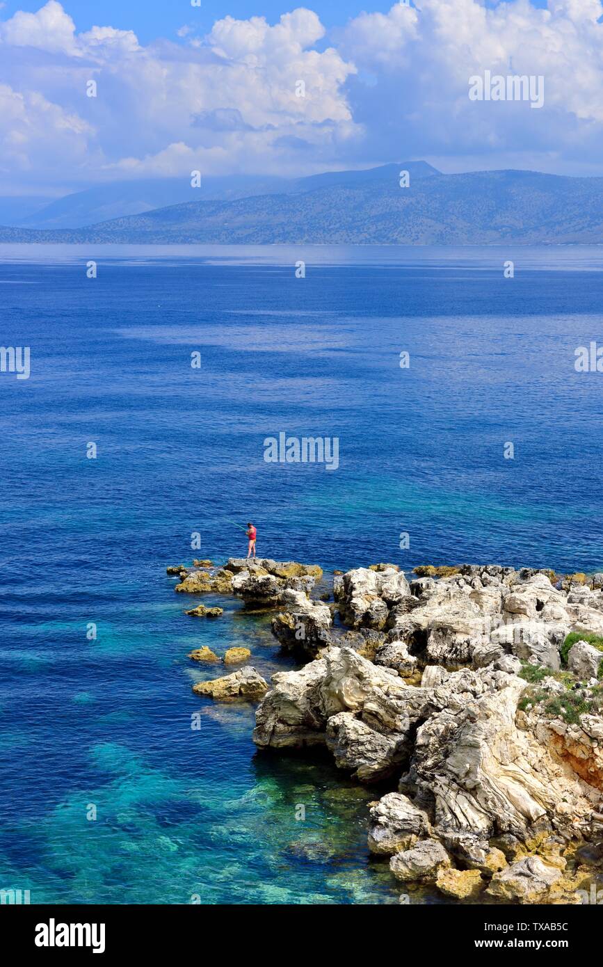 Un homme de pêche quelques roches à Kassiopi,Kassopaia,Îles Ioniennes, Corfou, Grèce Banque D'Images