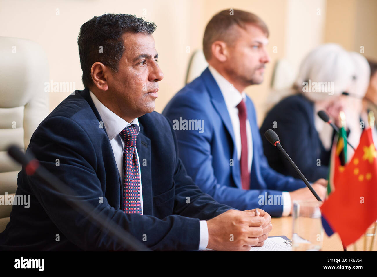 Homme politique sérieux à maturité à l'écoute de l'un de ses collègues Banque D'Images