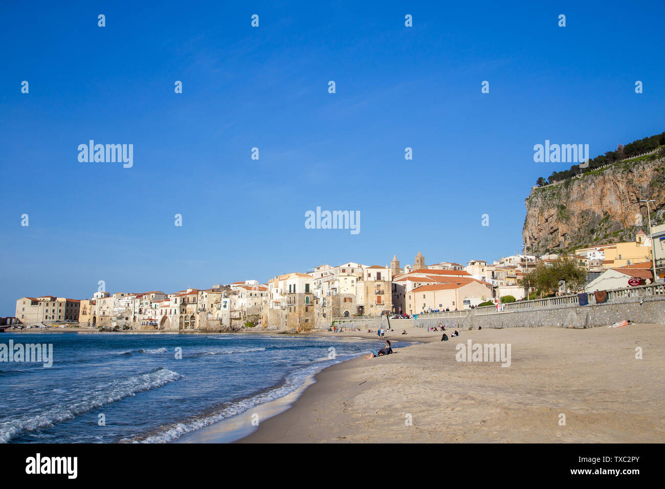 Céfalu, Sicile, Italie - 16 mars 2018 : une journée ensoleillée à la plage de Céfalu, avec peu de gens et méconnaissable vieux bâtiments typiques Banque D'Images