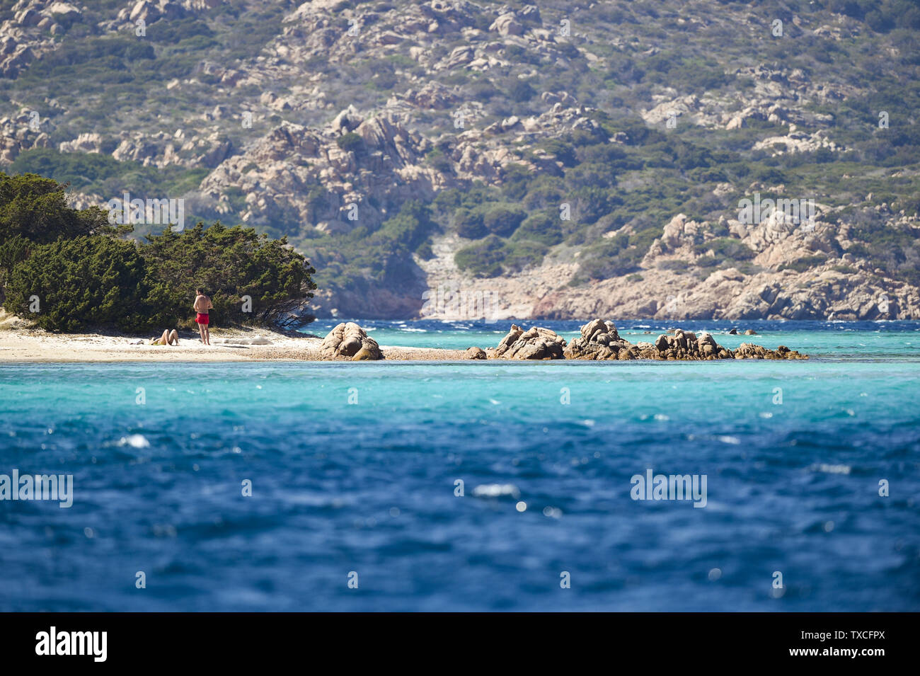 Un couple non identifiés sont les bains de soleil sur la magnifique plage de Spiaggia di Cavalieri (Cavalieri) baignée par une mer turquoise clair. L'archipel de La Maddalena Banque D'Images