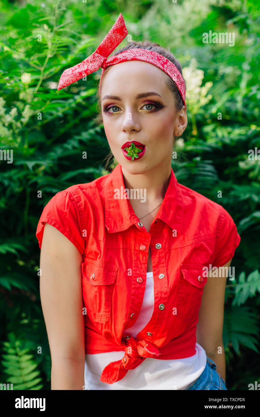 Belle jeune fille pin up habillé en chemise rouge avec des produits frais  et de fraise naturel dans la bouche Photo Stock - Alamy