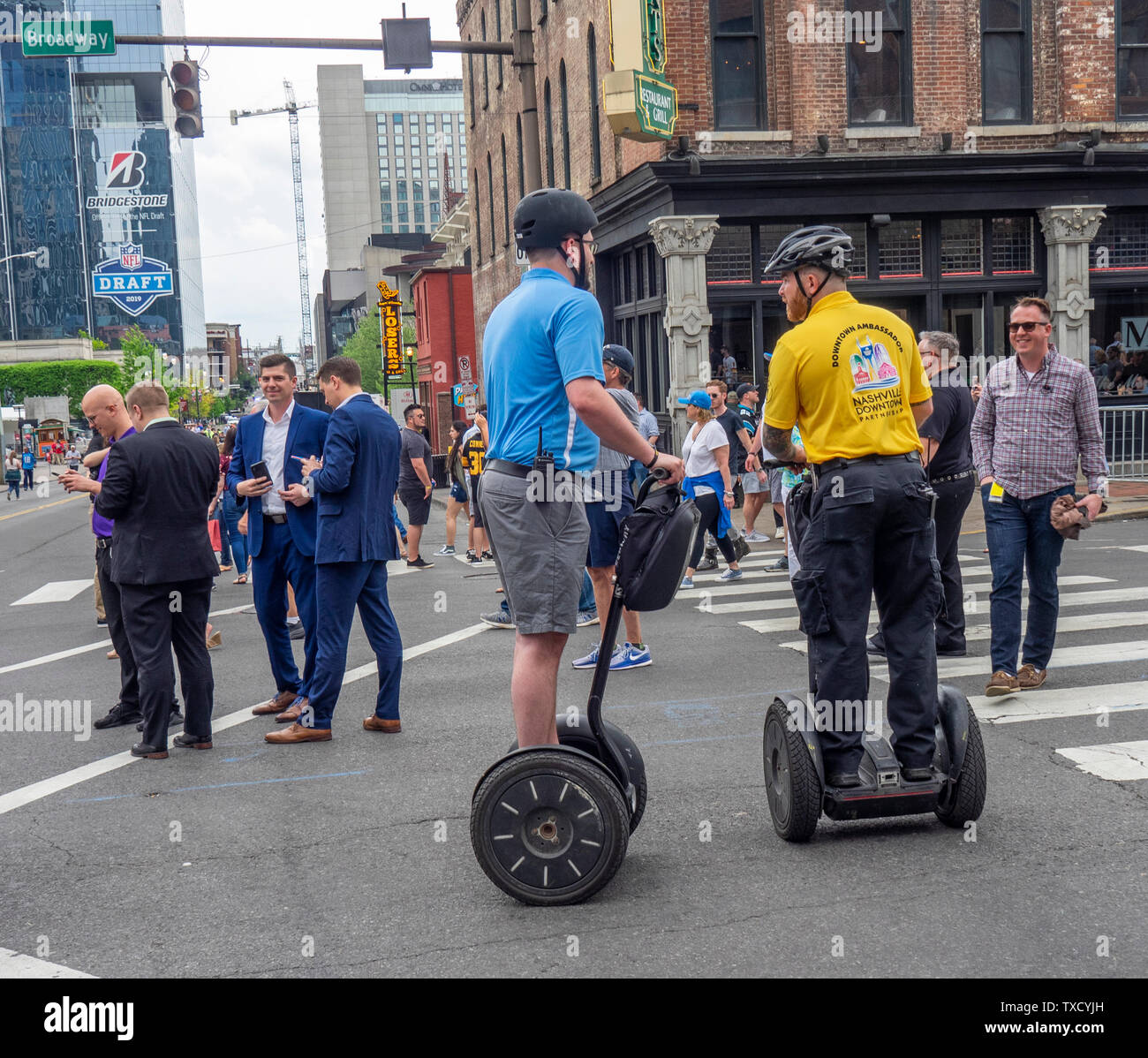 Fans de marcher le long de Broadway et deux hommes sur Segway PT transporteur personnel à deux roues motrices de NFL 2019 Nashville Tennessee USA. Banque D'Images