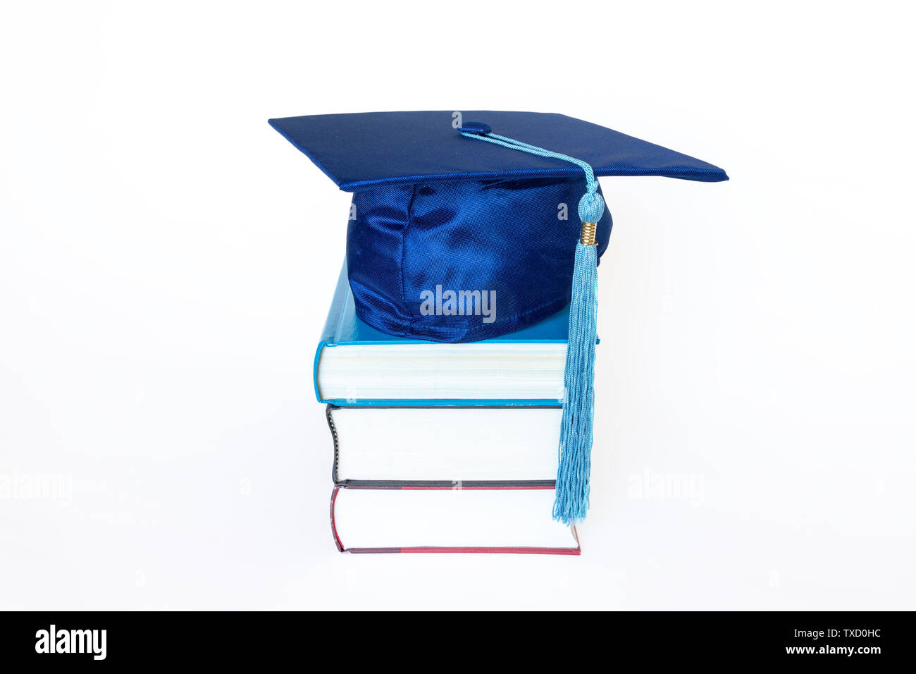 Graduation cap bleu avec pompon sur le dessus du livre isolé sur fond blanc. Concept de l'éducation. Banque D'Images