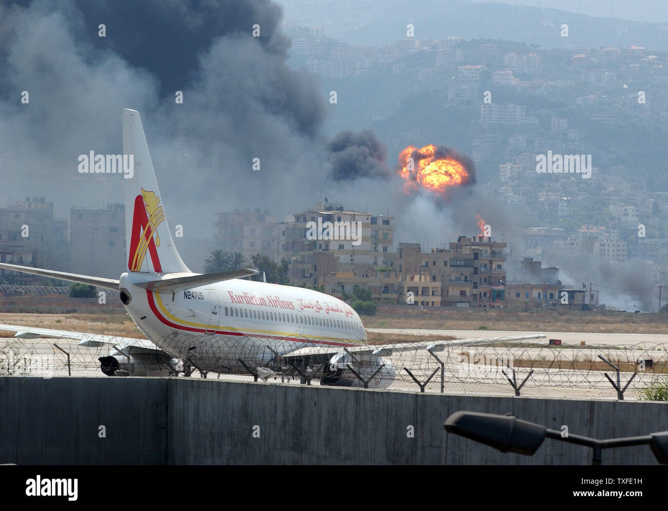 Un jet de passagers abandonnés se trouve sur la piste à l'aéroport international de Beyrouth comme un dépôt de stockage de carburant qui a été bombardée dans la nuit brûle dans l'arrière-plan le vendredi, Juillet 14, 2006. Le nombre de morts au Liban a adopté 50 depuis le bombardement a commencé le mercredi après que le Hezbollah guérilleros kidnappé deux soldats israéliens. (Photo d'UPI/Norbert Schiller) Banque D'Images