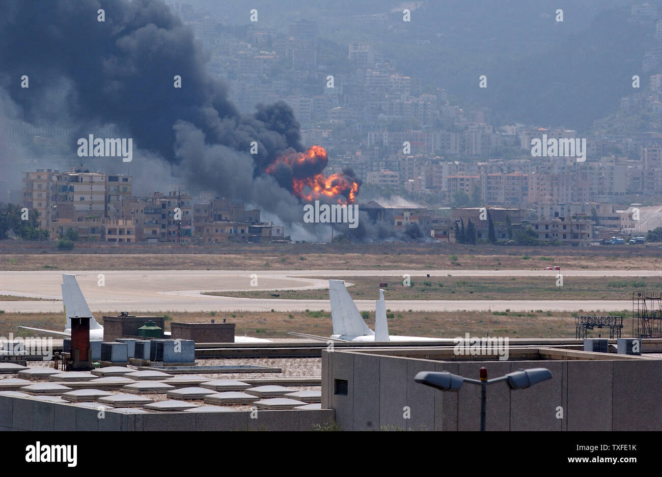 Un jet de passagers abandonnés se trouve sur la piste à l'aéroport international de Beyrouth comme un dépôt de stockage de carburant qui a été bombardée dans la nuit brûle dans l'arrière-plan le vendredi, Juillet 14, 2006. Le nombre de morts au Liban a adopté 50 depuis le bombardement a commencé le mercredi après que le Hezbollah guérilleros kidnappé deux soldats israéliens. (Photo d'UPI/Norbert Schiller) Banque D'Images