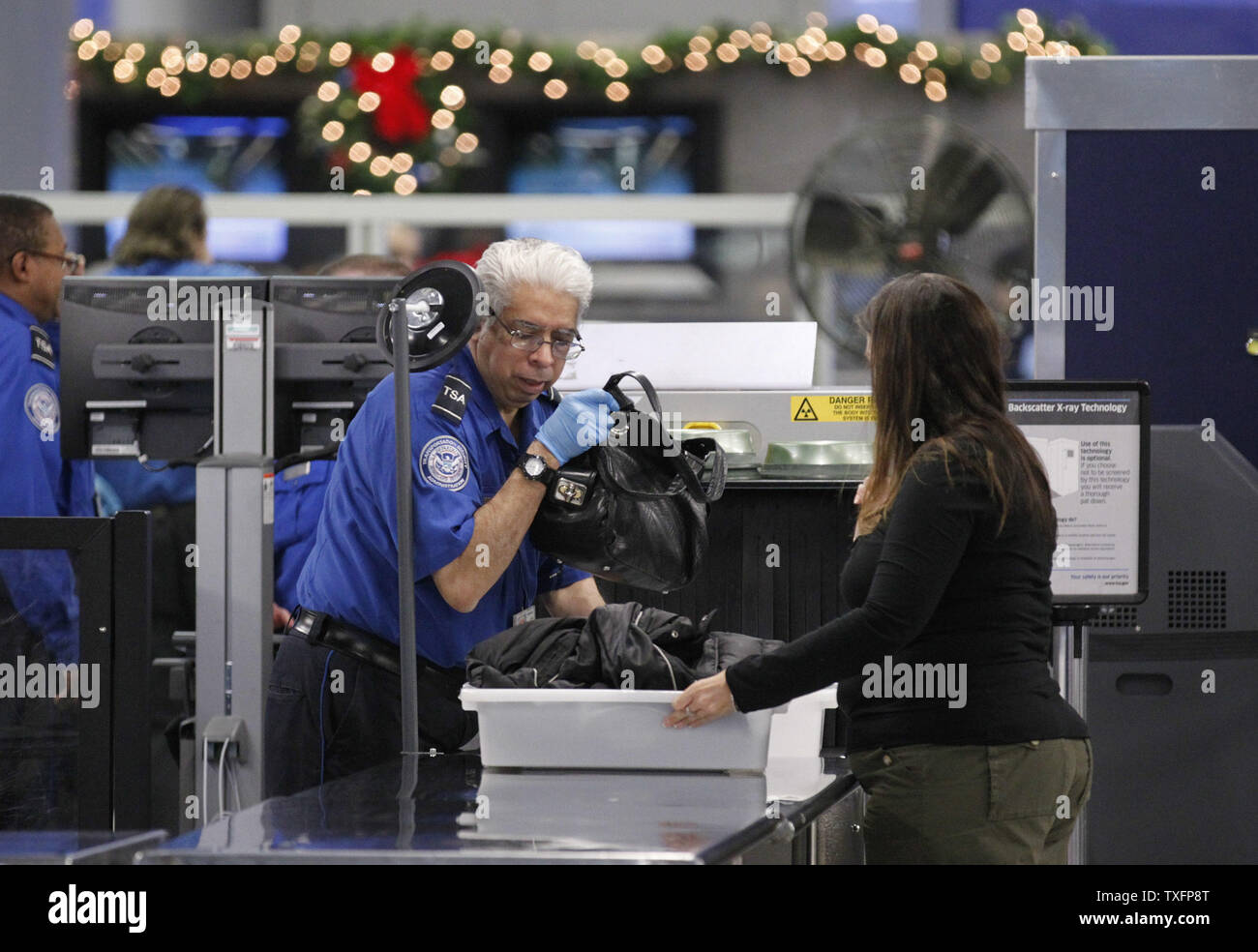 Une TSA screener aide un passager à un poste de contrôle de sécurité à l'aéroport international O'Hare le 24 novembre 2010 à Chicago. Fonctionne sans problème de sécurité le jour avant Thanksgiving en dépit des rumeurs de protestations de masse des procédures de sécurité. UPI/Brian Kersey Banque D'Images