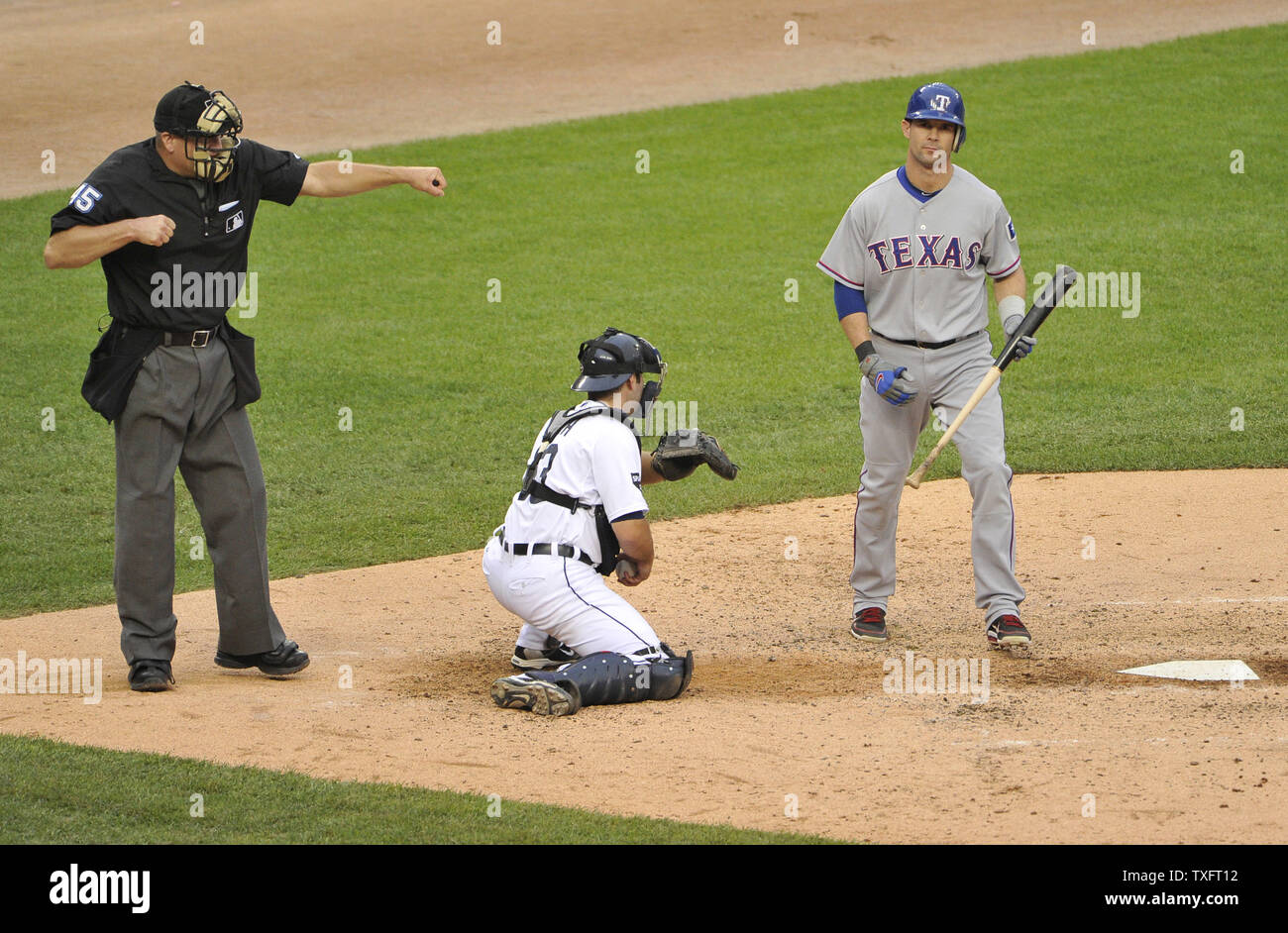 Les Rangers du Texas' Michael Young (R) frappe dehors que Detroit Tigers catcher Alex Avila (C) détient la balle et juge-arbitre Jeff Nelson les signaux au cours de la cinquième manche du Match 5 de la série de championnat de la ligue américaine à Comerica Park le 13 octobre 2011 à Detroit, Michigan. UPI/Brian Kersey Banque D'Images
