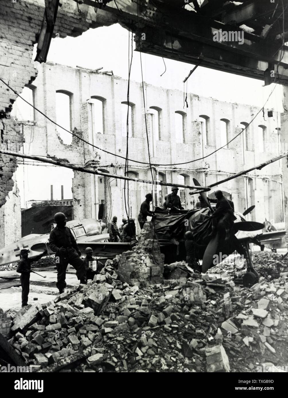 L'inspection des troupes de quartier-maître et la dépose des pièces provenant de la masse avion de chasse trouvés à l'intérieur d'une usine bombardée à Oschersleben, Allemagne. Banque D'Images