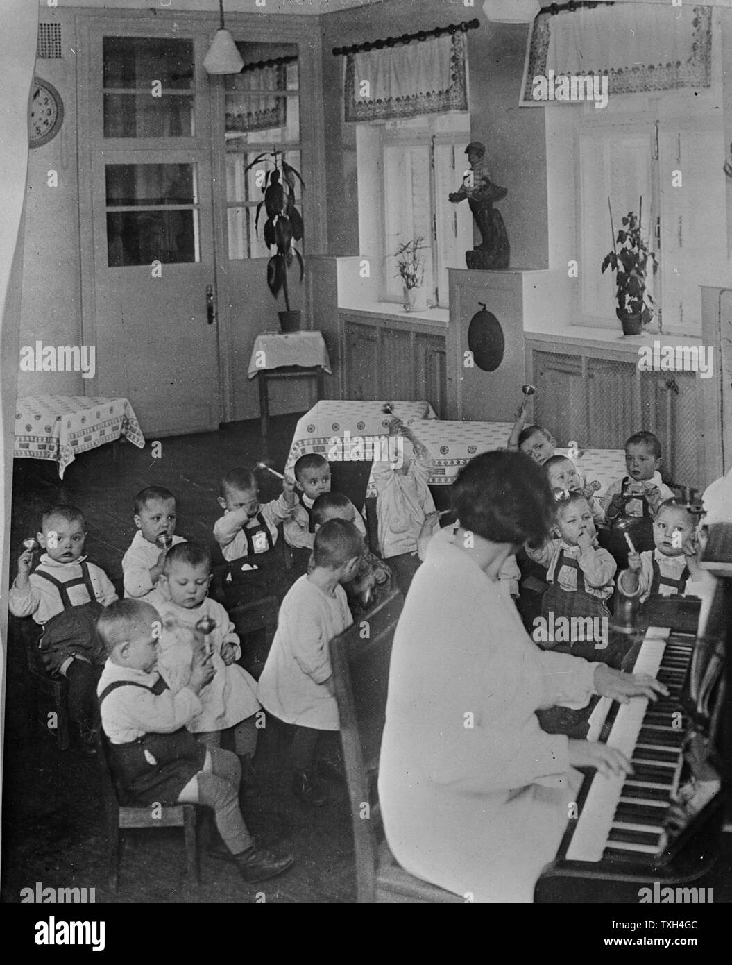 L'école maternelle avec des enfants par femme au piano URSS 1930-1940. Banque D'Images