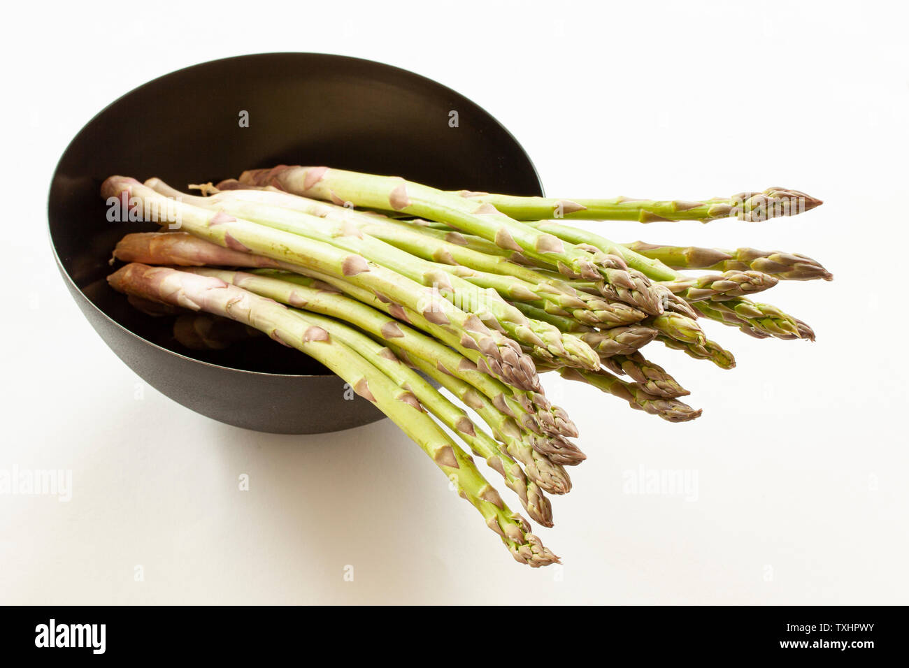 Ensemble de l'asperge verte dans un bol rond noir. Close up image. Banque D'Images