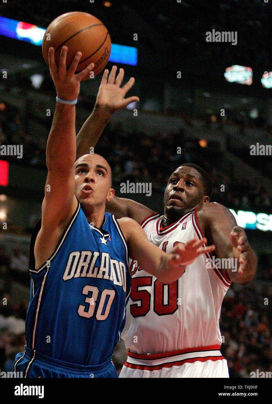 Le Orlando Magic Carlos Arroyo (30) va jusqu'à un tir que Chicago Bulls' Michael Sweetney (50) défend au cours du premier trimestre d'un match de basket-ball NBA à Chicago le 28 mars 2006. (Photo d'UPI/Brian Kersey) Banque D'Images