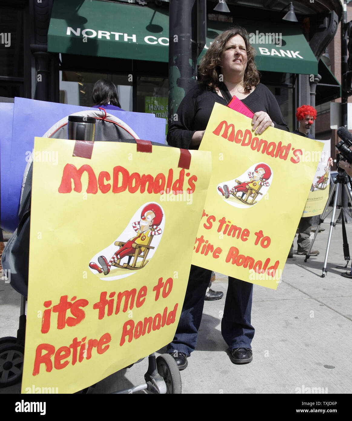 Tracy Kostenbader détient des signes appelant à la retraite de Ronald McDonald est une mascotte pour la chaîne de fast-food au cours d'une manifestation à Chicago le 31 mars 2010. Les manifestants, organisé par Corporate Accountability International, la revendication McDonald's utilise la mascotte de l'entreprise sur le marché des aliments gras malsains, aux enfants. UPI/Brian Kersey Banque D'Images