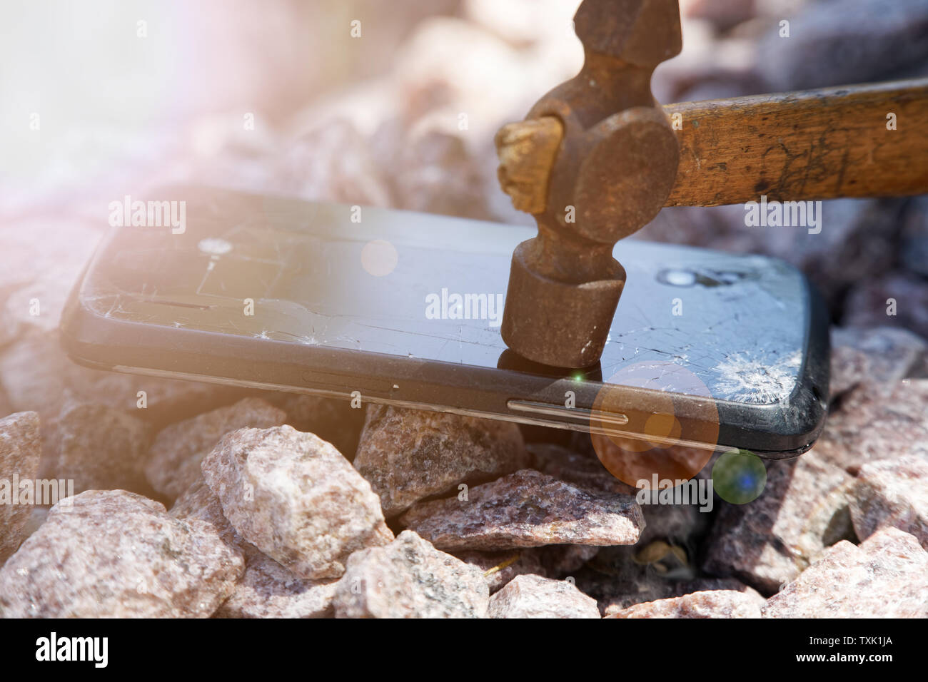 Broken Glass de smartphone avec marteau sur des cailloux. Focus sélectif et feux de route. Banque D'Images