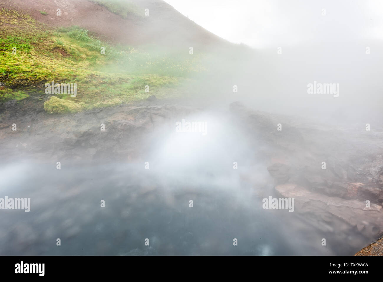 Gros plan du geyser de vapeur à Deildartunguhver hot springs en Islande avec une longue exposition nuageux brouillard brouillard qui sort de la grotte de vapeur d'eau bouillante Banque D'Images