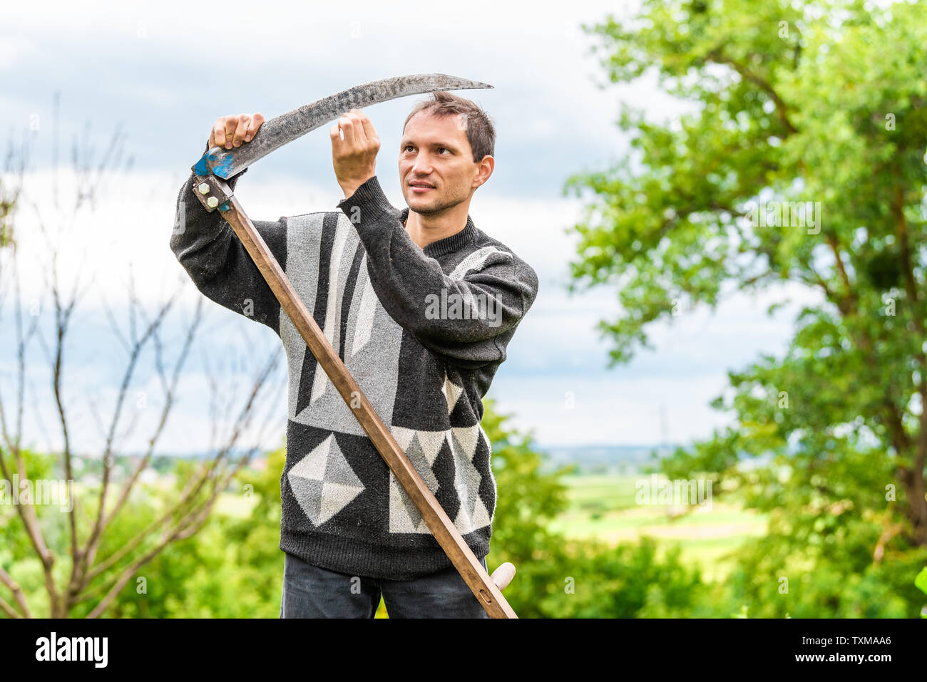 Homme heureux agriculteur au jardin d'affûtage permanent faux faucille outil  râteau en vert l'été à l'Ukraine par les plantes agricoles Photo Stock -  Alamy