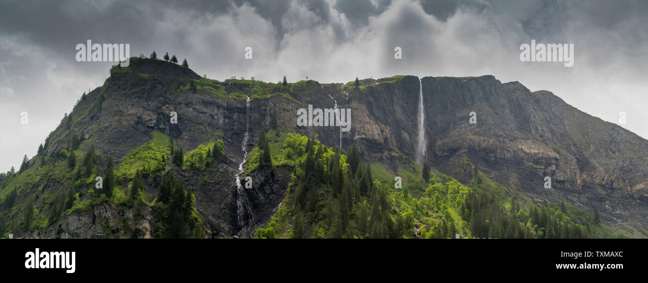 Panorama Mountain paysage avec une forêt luxuriante et plusieurs chutes d'eau dans les Alpes Suisses sous un ciel couvert journée d'été Banque D'Images