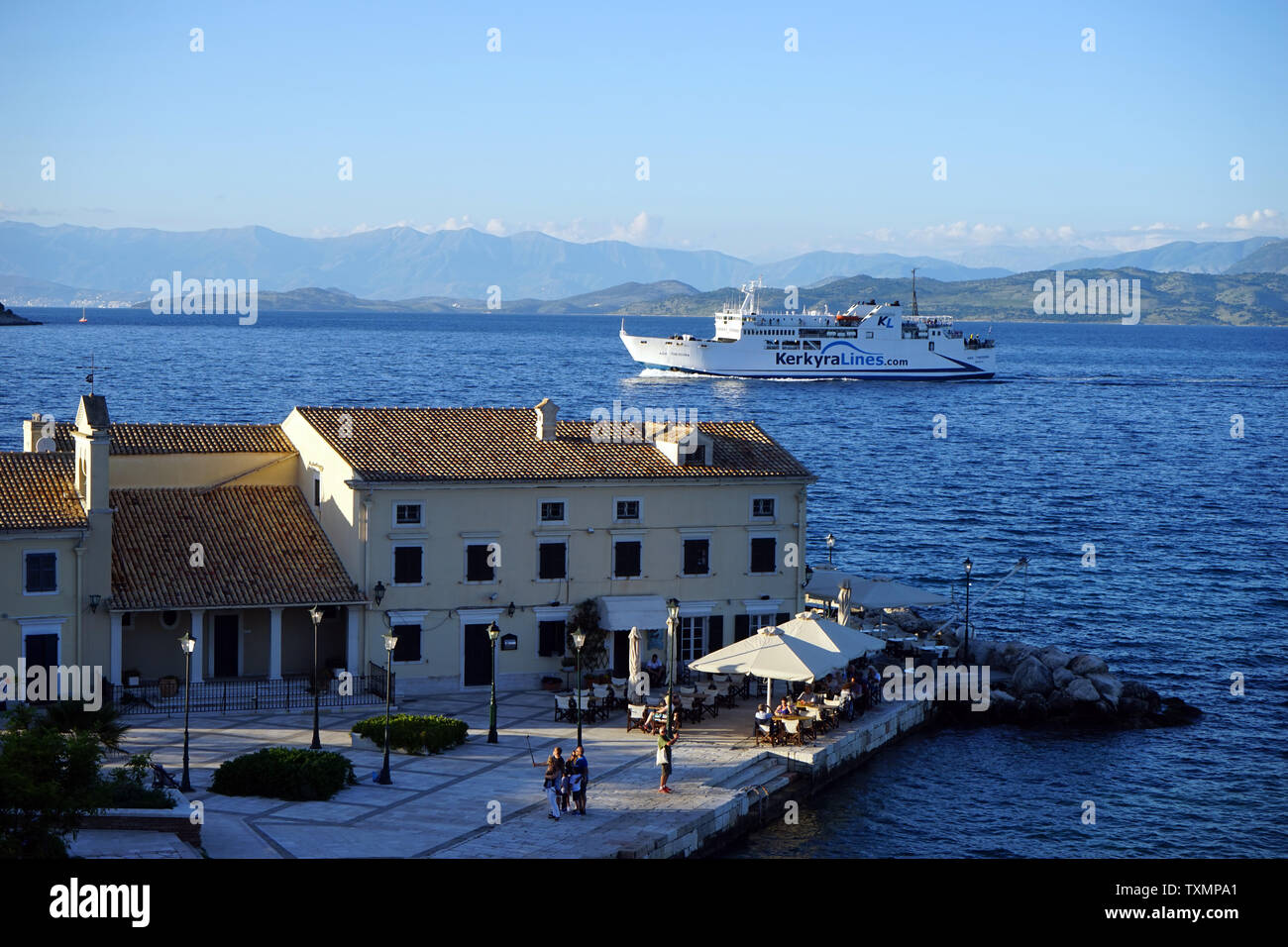 Corfou, Grèce - CIRCA MAI 2019 Restaurant sur le port et ferry boat Banque D'Images