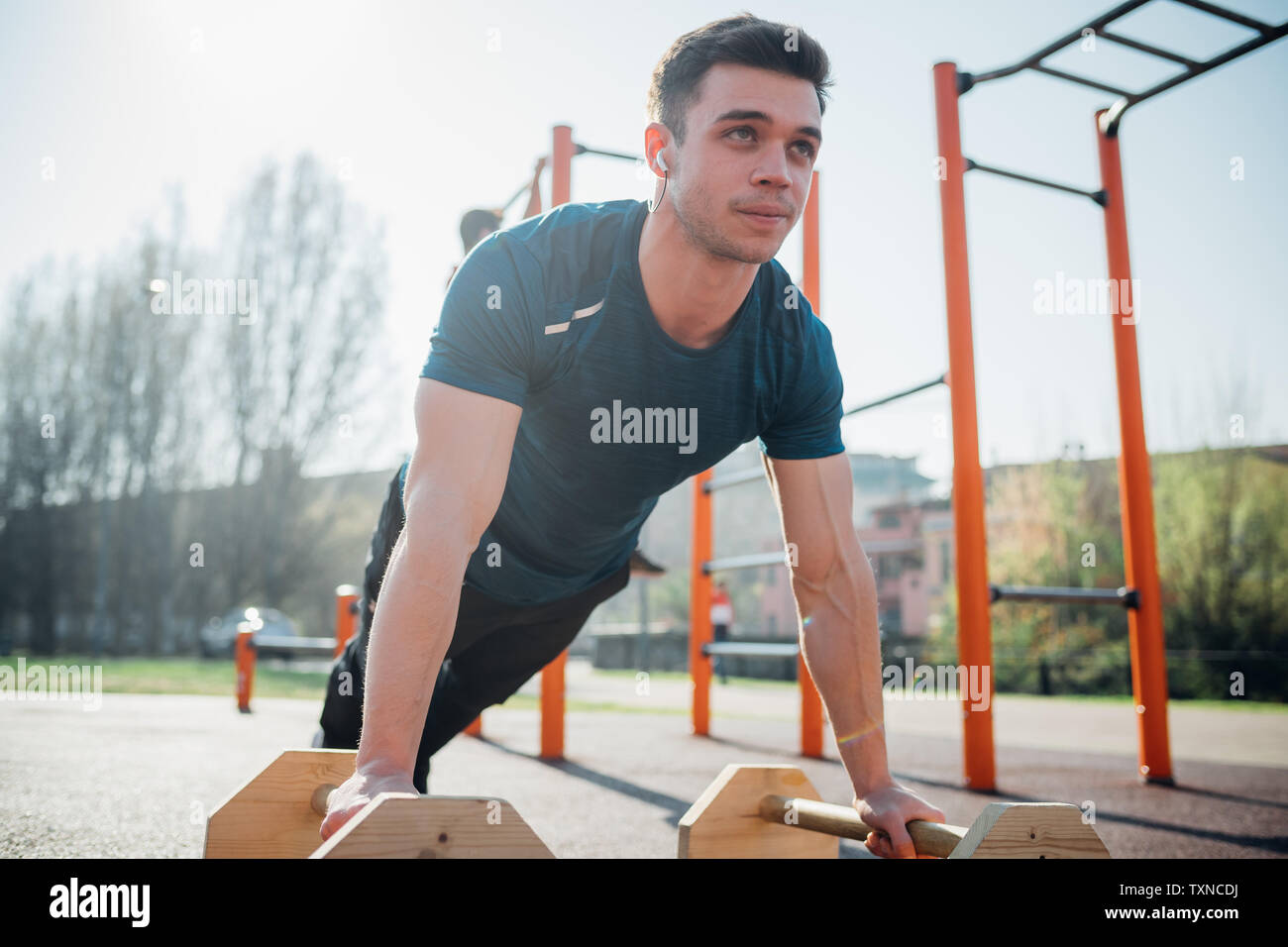 La gymnastique au sport en plein air, jeune homme faire poussez se lève sur l'équipement d'exercice Banque D'Images