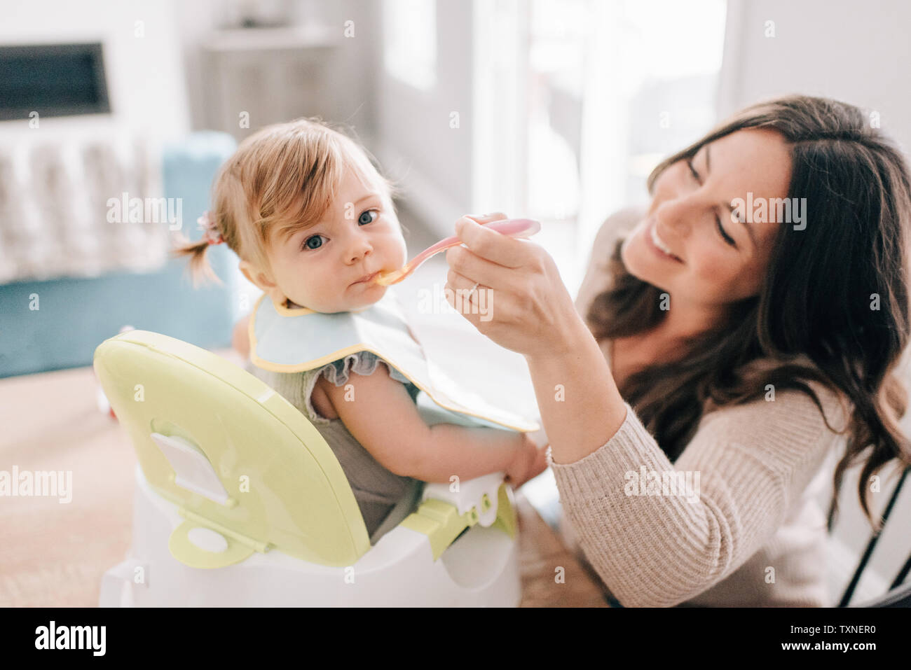 Mère nourrir bébé fille dans un siège pour enfant, portrait Banque D'Images