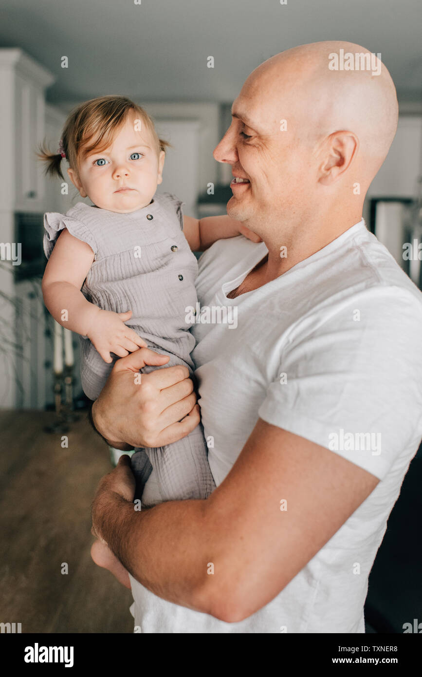 Father carrying baby fille dans la salle de séjour, portrait Banque D'Images