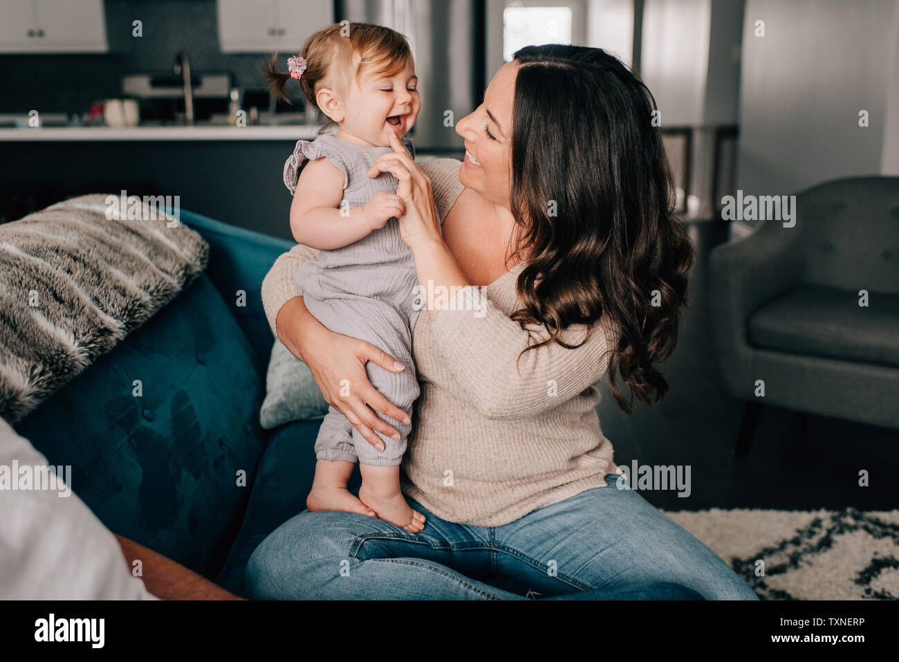 Mère jouant avec sa petite fille sur canapé Banque D'Images