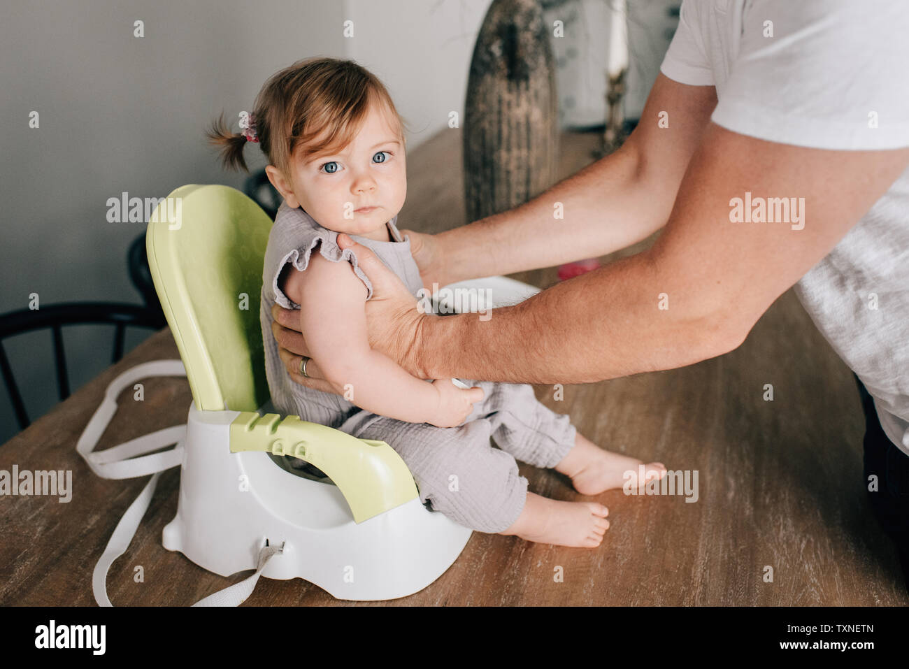 Père de mettre sa petite fille à siège enfant, cropped portrait Banque D'Images