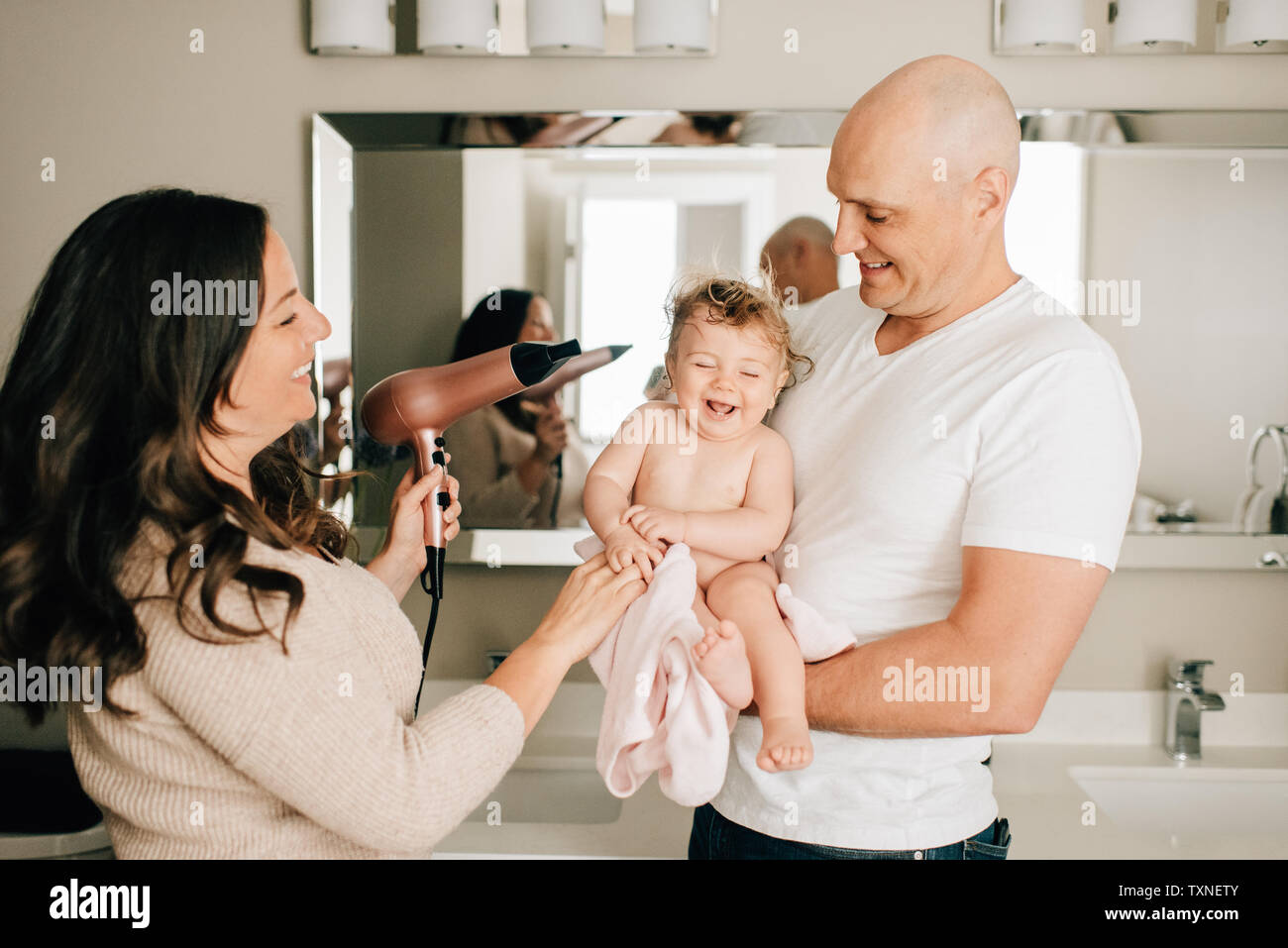 Mère et père de la fille de bébé de séchage des cheveux dans salle de bains Banque D'Images