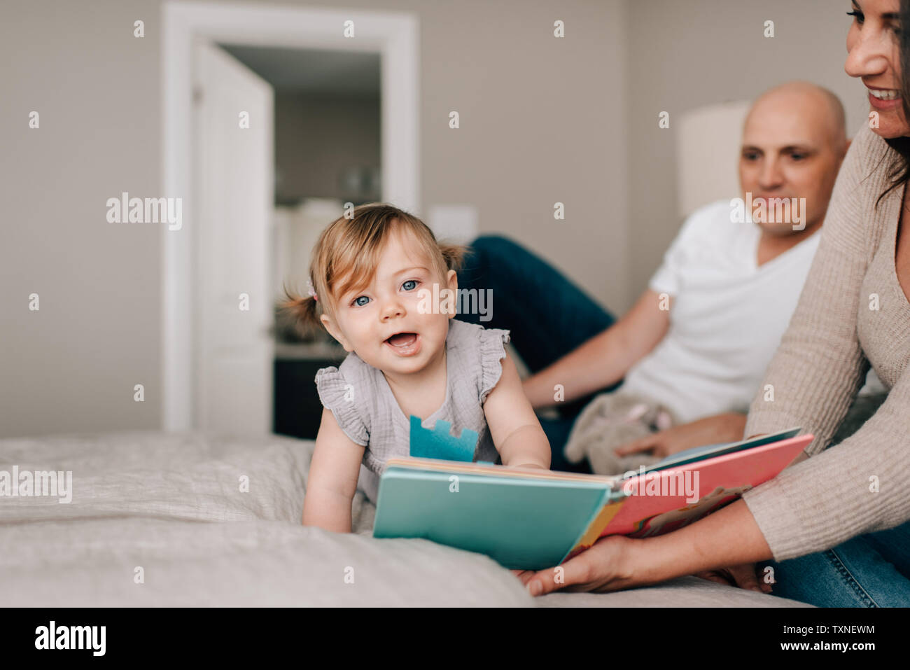 Père et mère sur le lit avec sa petite fille avec story book, portrait Banque D'Images