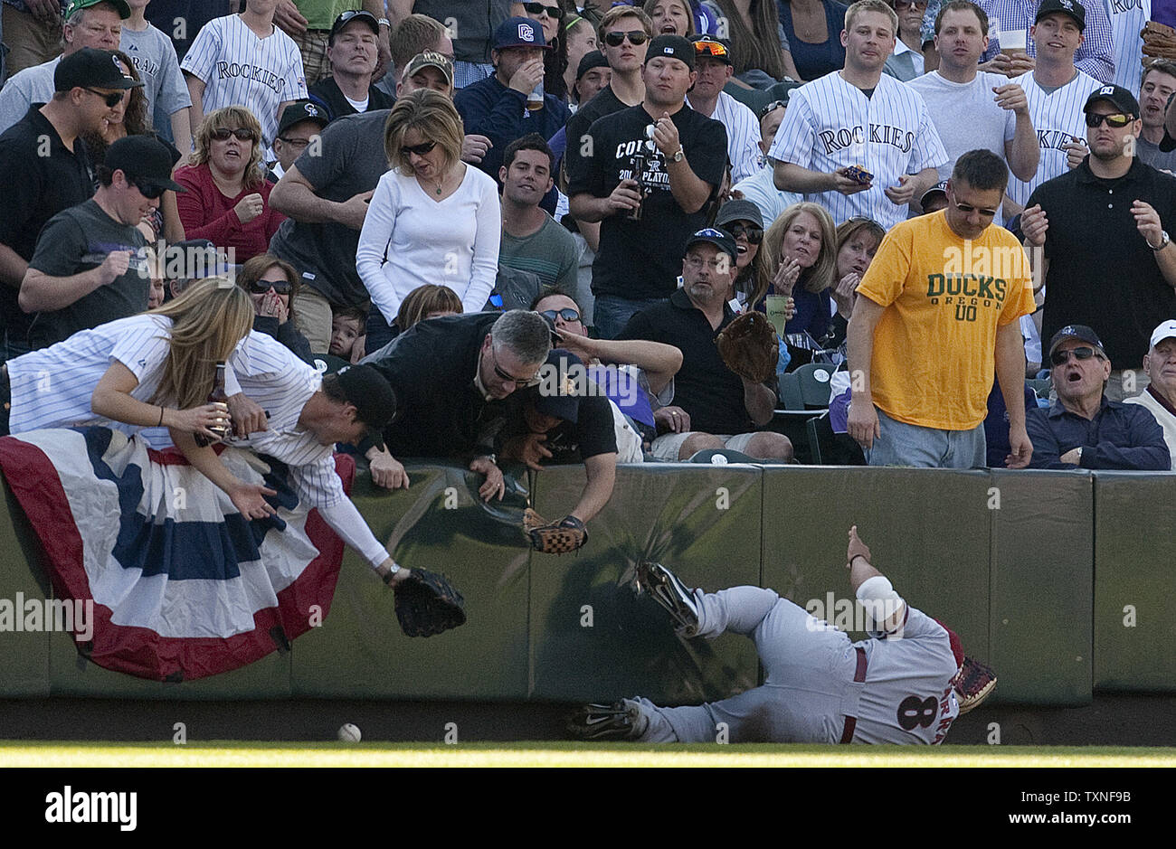 Un ventilateur tente d'attraper un Colorado Rockies Todd Helton fausse balle vers le bas la ligne de champ gauche avec Arizona le voltigeur Diamondsback Gerardo Parra glissant à tenter d'attraper à Coors Field le jour d'ouverture à Denver le 1 er avril 2011. Helton a été écartée par la troisième base juge-arbitre Loi Welke avec une apparente ingérence ventilateur appel. UPI/Gary C. Caskey Banque D'Images