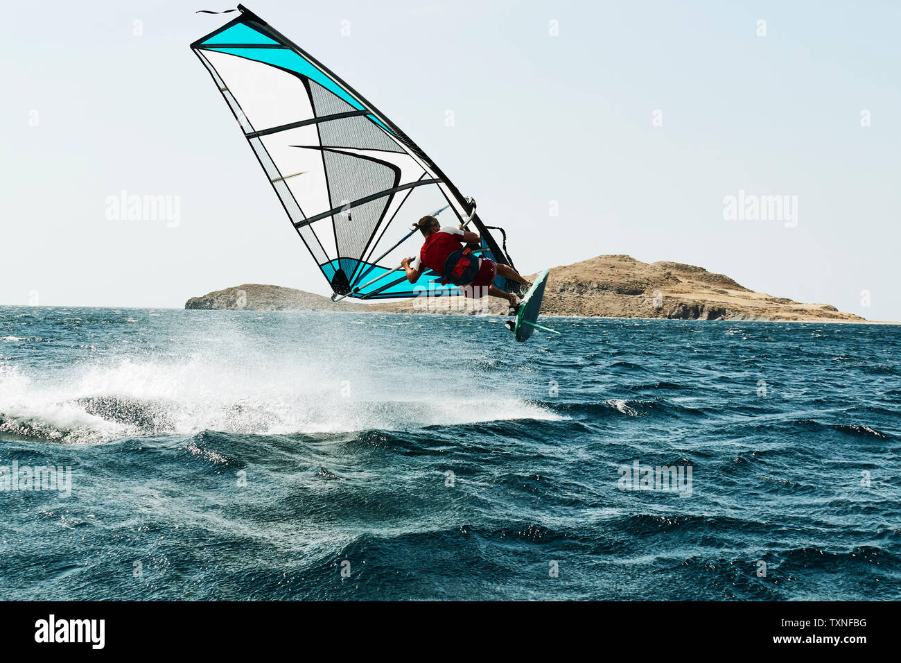 Jeune homme planche à voile au-dessus des vagues de l'océan, vue arrière, Limnos, Calino, Grèce Banque D'Images