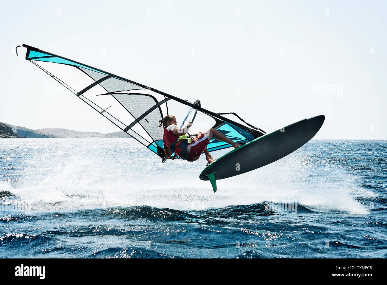 Jeune homme planche à voile au-dessus des vagues de l'océan, Limnos, Calino, Grèce Banque D'Images