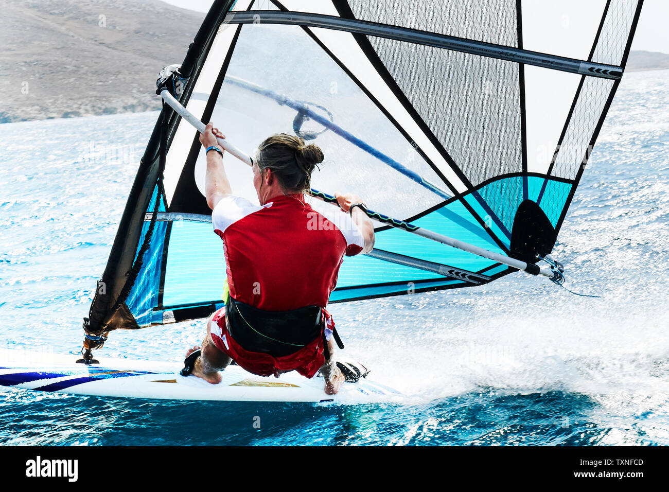 Jeune homme planche à voile océan vagues, vue arrière, Limnos, Calino, Grèce Banque D'Images