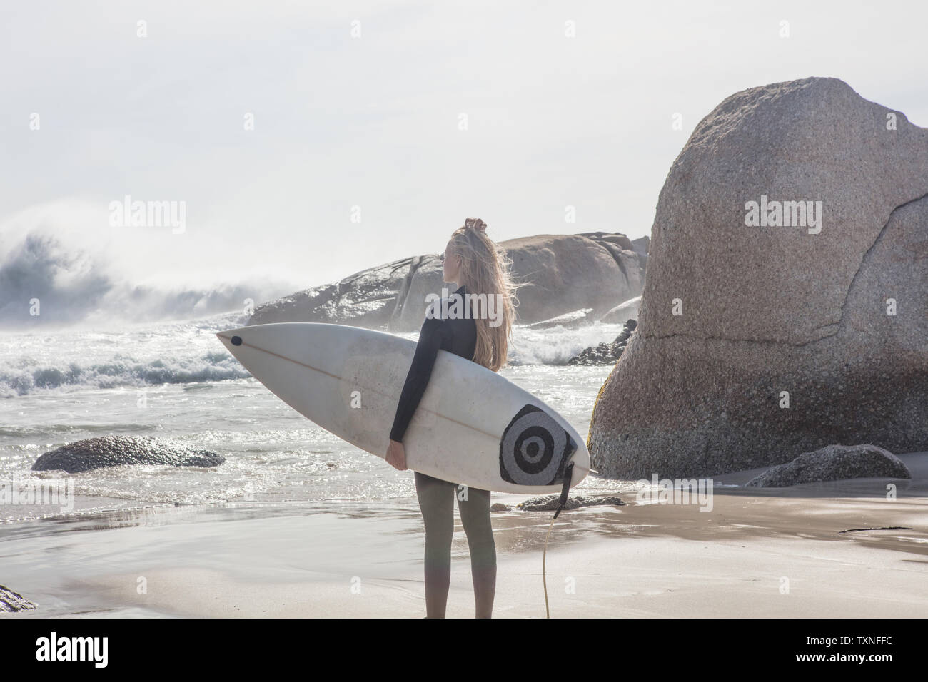 Jeune femme surfer carrying surfboard en voyant les vagues de l'océan à partir de la plage, à Cape Town, Western Cape, Afrique du Sud Banque D'Images