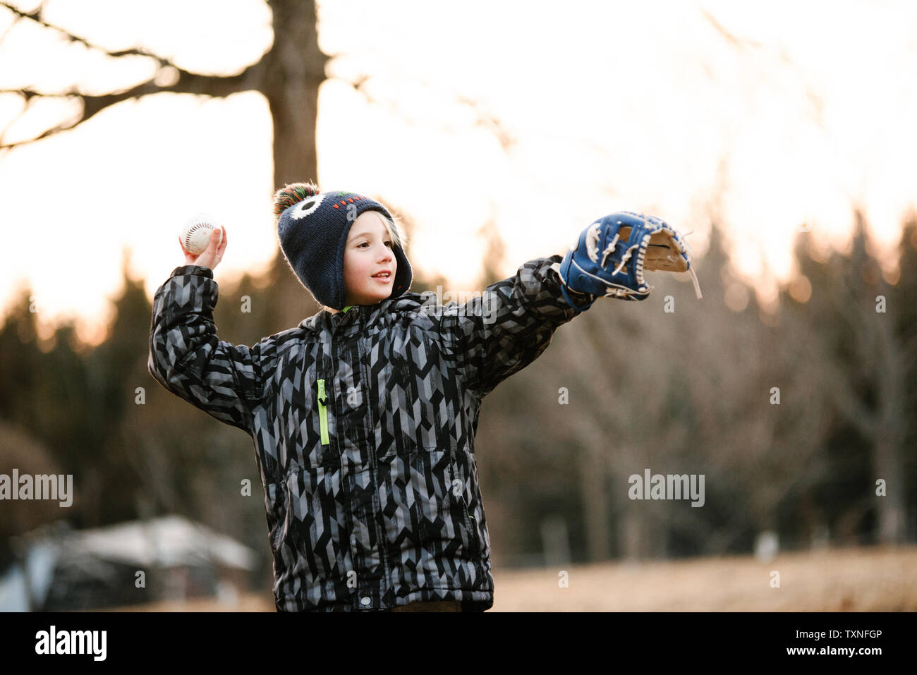 Boy preparing to throw baseball ball in rural field Banque D'Images