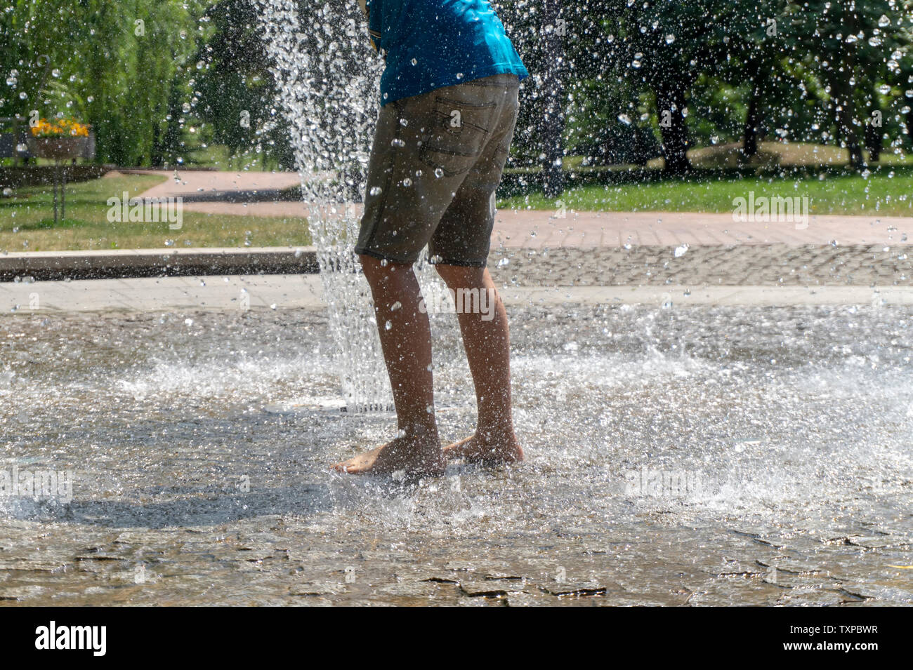Personne Barefoot running through une fontaine dans le jet d'eau dans un low angle view of leurs jambes Banque D'Images