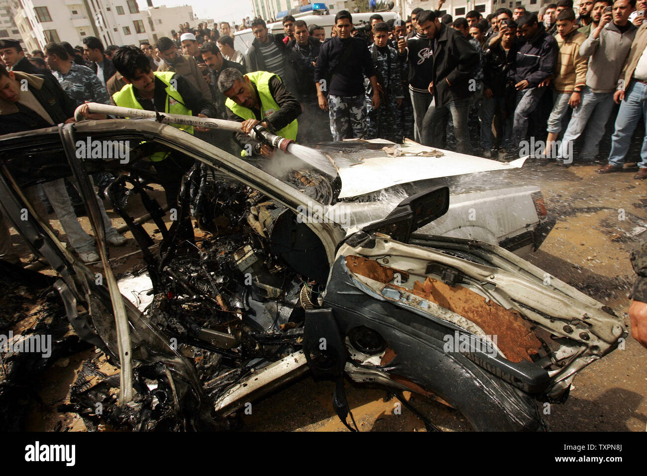 Les travailleurs d'urgence civile palestinienne pour éteindre un véhicule en feu après une explosion à Gaza le 1 mars 2006. Un haut commandant du Jihad islamique a été tué dans une explosion de voiture à Gaza mercredi que les témoins ont dit a été causée par une frappe aérienne israélienne. L'armée israélienne n'avait aucun commentaire immédiat.(Photo UPI/Ismael Mohamad) Banque D'Images