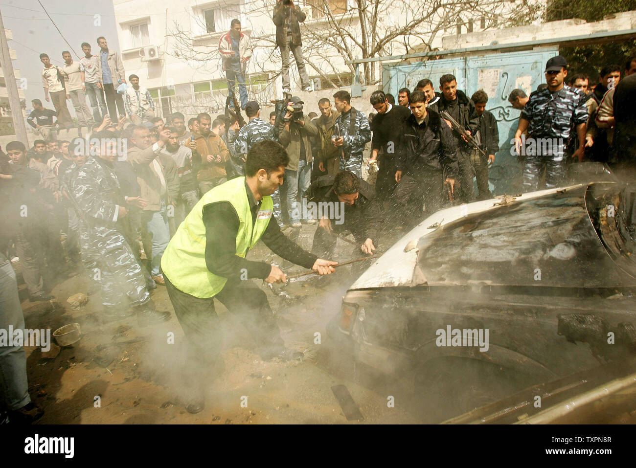 Les travailleurs d'urgence civile palestinienne pour éteindre un véhicule en feu après une explosion à Gaza le 1 mars 2006. Un haut commandant du Jihad islamique a été tué dans une explosion de voiture à Gaza mercredi que les témoins ont dit a été causée par une frappe aérienne israélienne. L'armée israélienne n'avait aucun commentaire immédiat.(Photo UPI/Ismael Mohamad) Banque D'Images