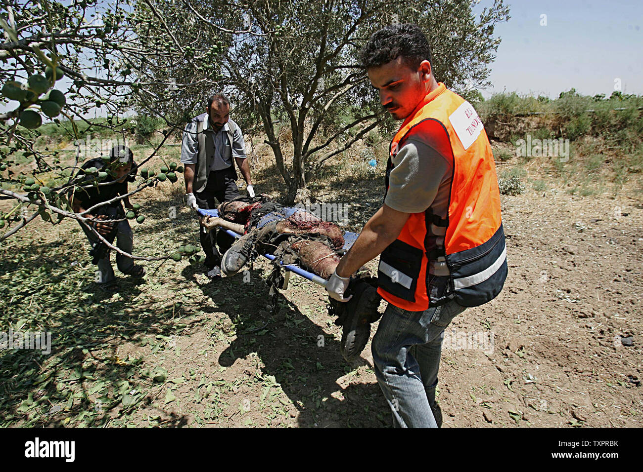 Le corps du combattant palestinien Yousif Khalil de Joha Ezz El-Deen Al-Qassam l'aile militaire du mouvement de la Résistance islamique, le Hamas, est enlevé par les ambulanciers de sous un olivier après qu'il a été ciblé par un missile à partir d'un avion sans pilote israélien au cours d'affrontements le 27 juin 2007. Les forces israéliennes ont tué au moins 13 Palestiniens, pour la plupart des combattants du Hamas, et environ 40 blessés au cours d'une offensive contre la bande de Gaza, a déclaré que les travailleurs médicaux. (Photo d'UPI/Ismael Mohamad) Banque D'Images