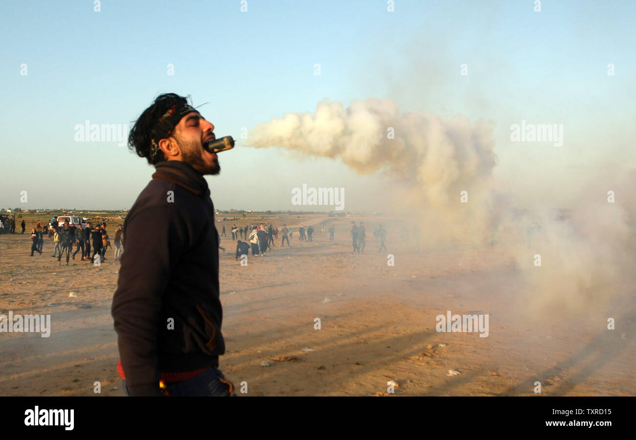 Un manifestant palestinien est titulaire d'une bombe lacrymogène dans sa bouche pendant une manifestation le long de la frontière avec Israël à l'est de Rafah, dans le sud de la bande de Gaza, le 8 février 2019. Deux Palestiniens, dont un adolescent ont été tués par des tirs israéliens le vendredi lors d'affrontements à la frontière de Gaza, le ministère de la santé a dit. Photo par Ismael Mohamad/UPI. Banque D'Images