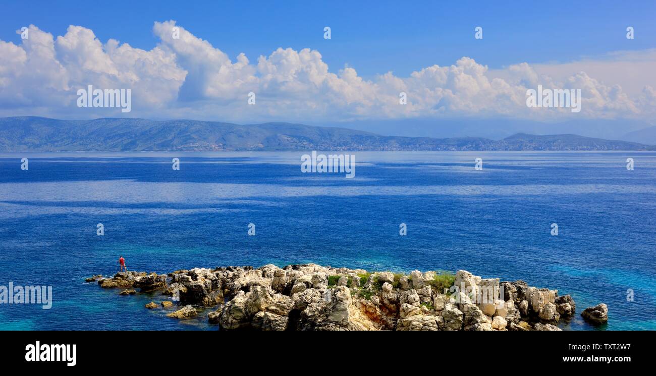 Un homme de pêche quelques roches à Kassiopi,Kassopaia,Îles Ioniennes, Corfou, Grèce Banque D'Images